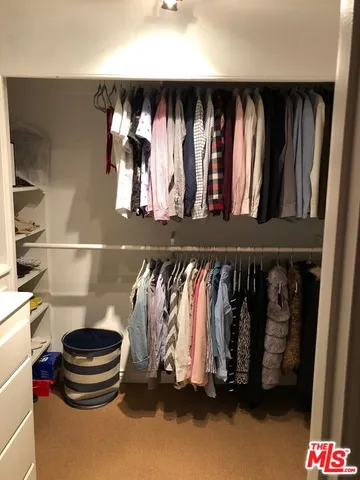 a view of walk in closet with clothes and shoes