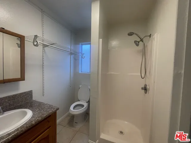 a bathroom with a granite countertop sink a toilet and shower