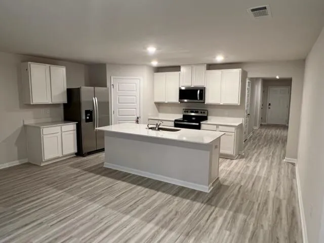 a large kitchen with cabinets a counter top space stainless steel appliances and a window