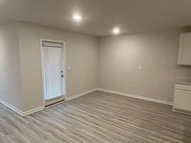 an empty room with wooden floor and windows