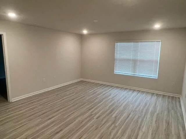 an empty room with wooden floor and windows