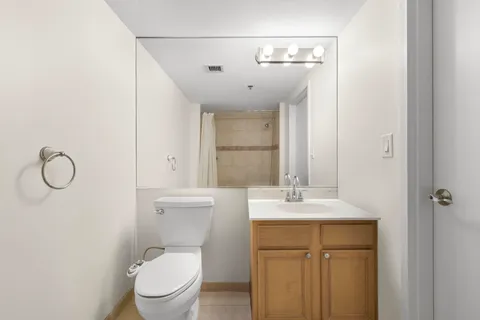 a bathroom with a toilet sink vanity and mirror