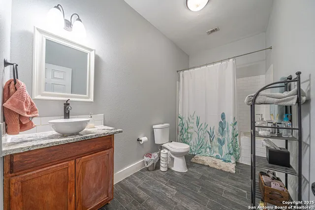 a bathroom with a granite countertop sink a toilet and a mirror
