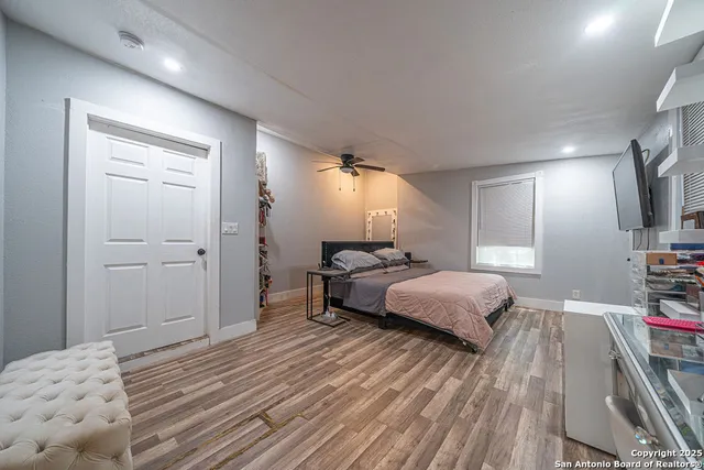 a spacious bedroom with a bed and a flat tv screen on dresser