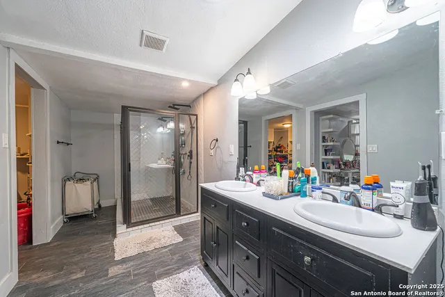 a bathroom with double vanity sinks a toilet a shower and a mirror