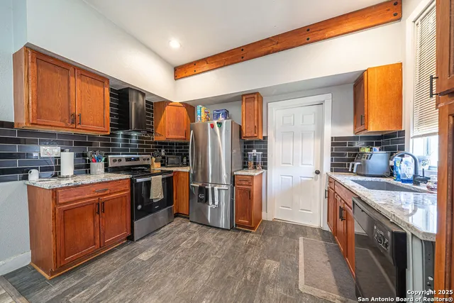 a kitchen with stainless steel appliances granite countertop a stove a sink dishwasher a refrigerator and cabinets with wooden floor