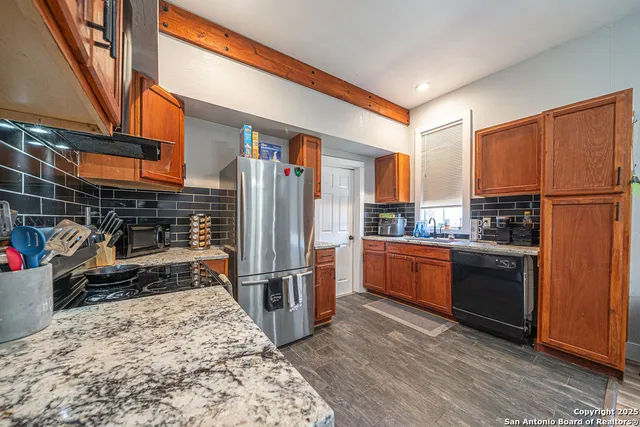 a kitchen with stainless steel appliances kitchen island granite countertop a refrigerator and a stove top oven