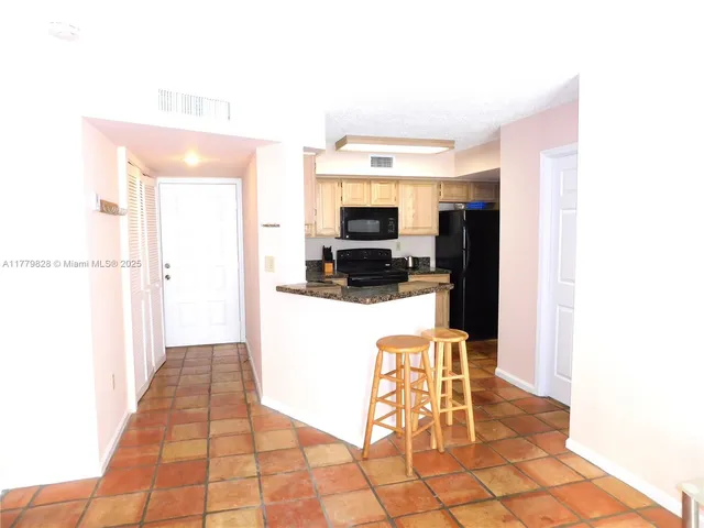 a living room with stainless steel appliances kitchen island granite countertop a refrigerator and a sink