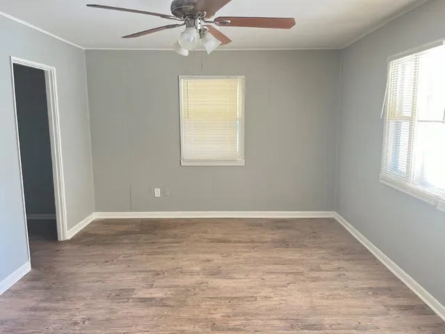 an empty room with windows and fan