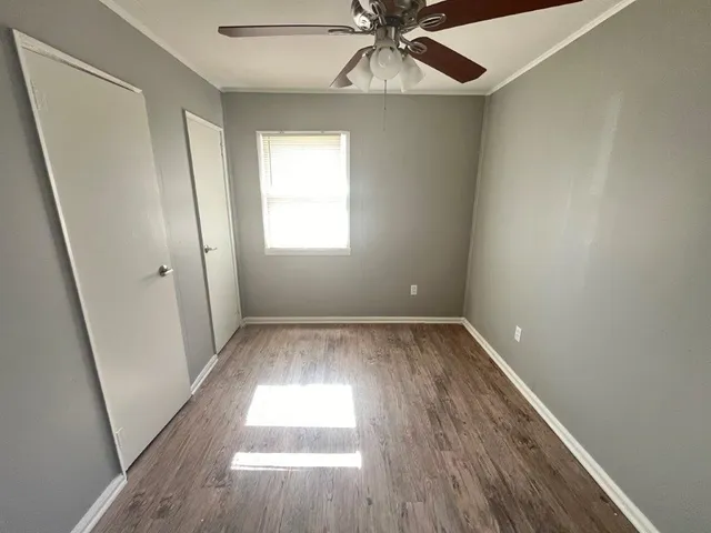 an empty room with wooden floor fan and windows