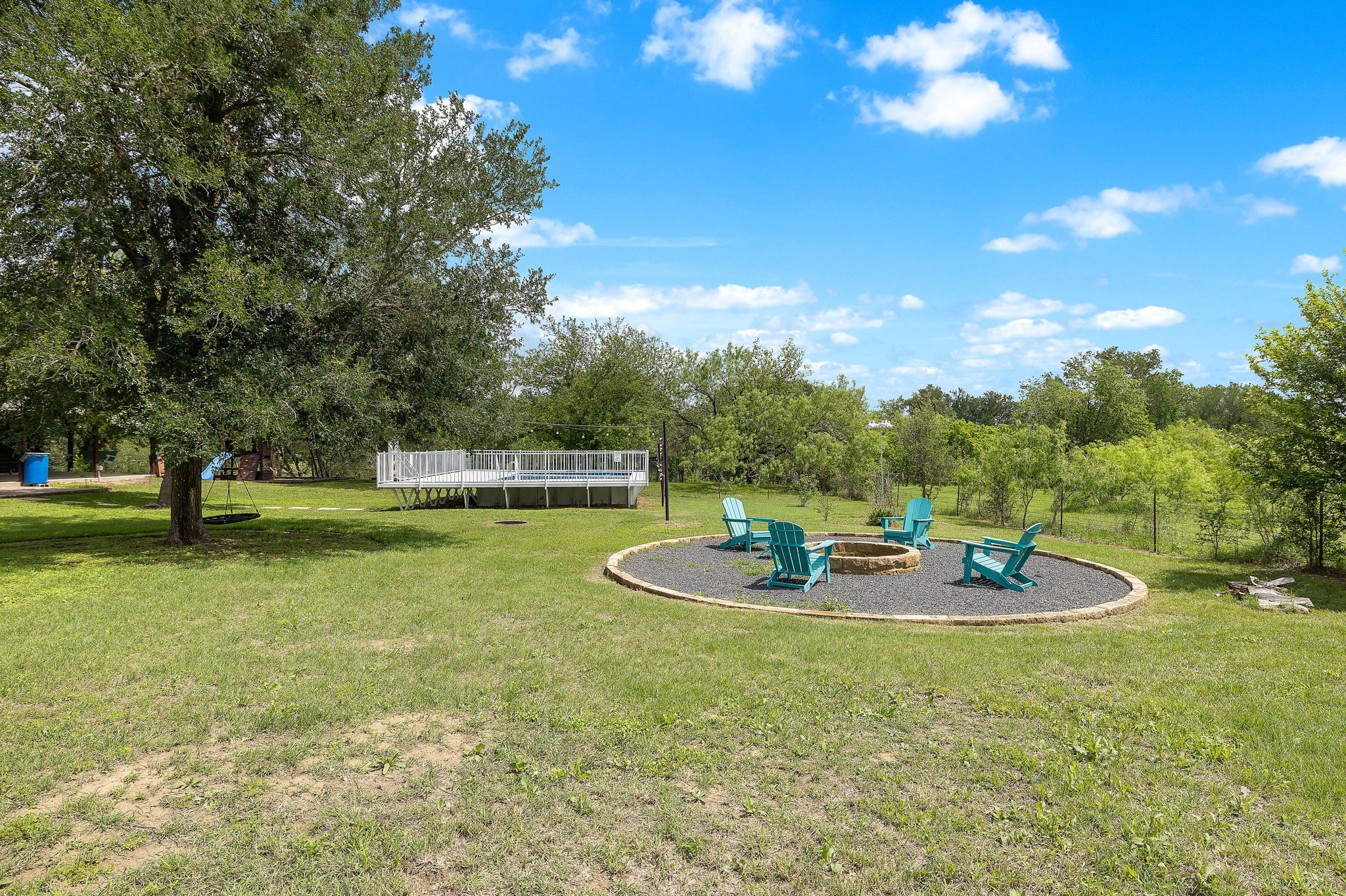 571 Balch Road Elgin, TX 78621 - Photo 25 of 33 Expansive grassy outdoor space featuring a stone-rimmed fire pit with dark gravel surround