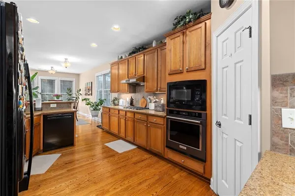 a kitchen with a refrigerator a stove top oven a sink dishwasher and wooden cabinets with wooden floor