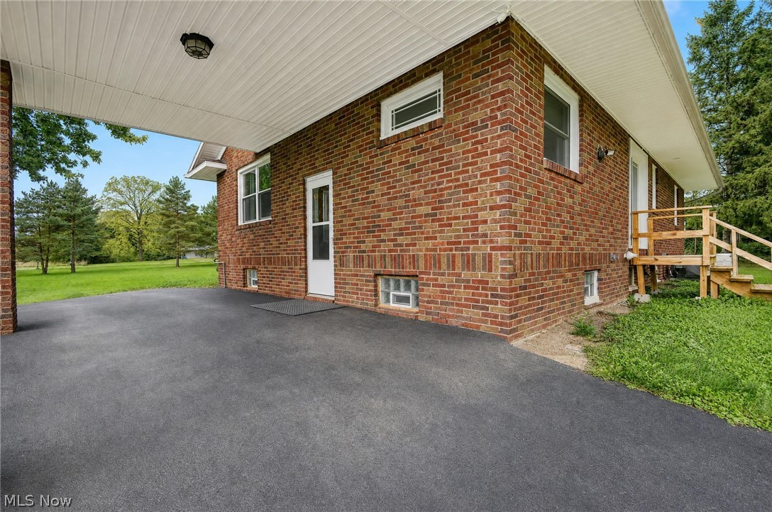 3864 State Road South Ashtabula, OH 44004 - Photo 3 of 50 Brick exterior featuring a covered carport, wood-frame windows, and a wooden exterior staircase