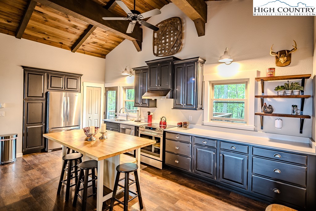 821 Pine Ridge Road Beech Mountain, NC 28604 - Photo 13 of 38 a kitchen with stainless steel appliances kitchen island granite countertop a table chairs in it and wooden floors