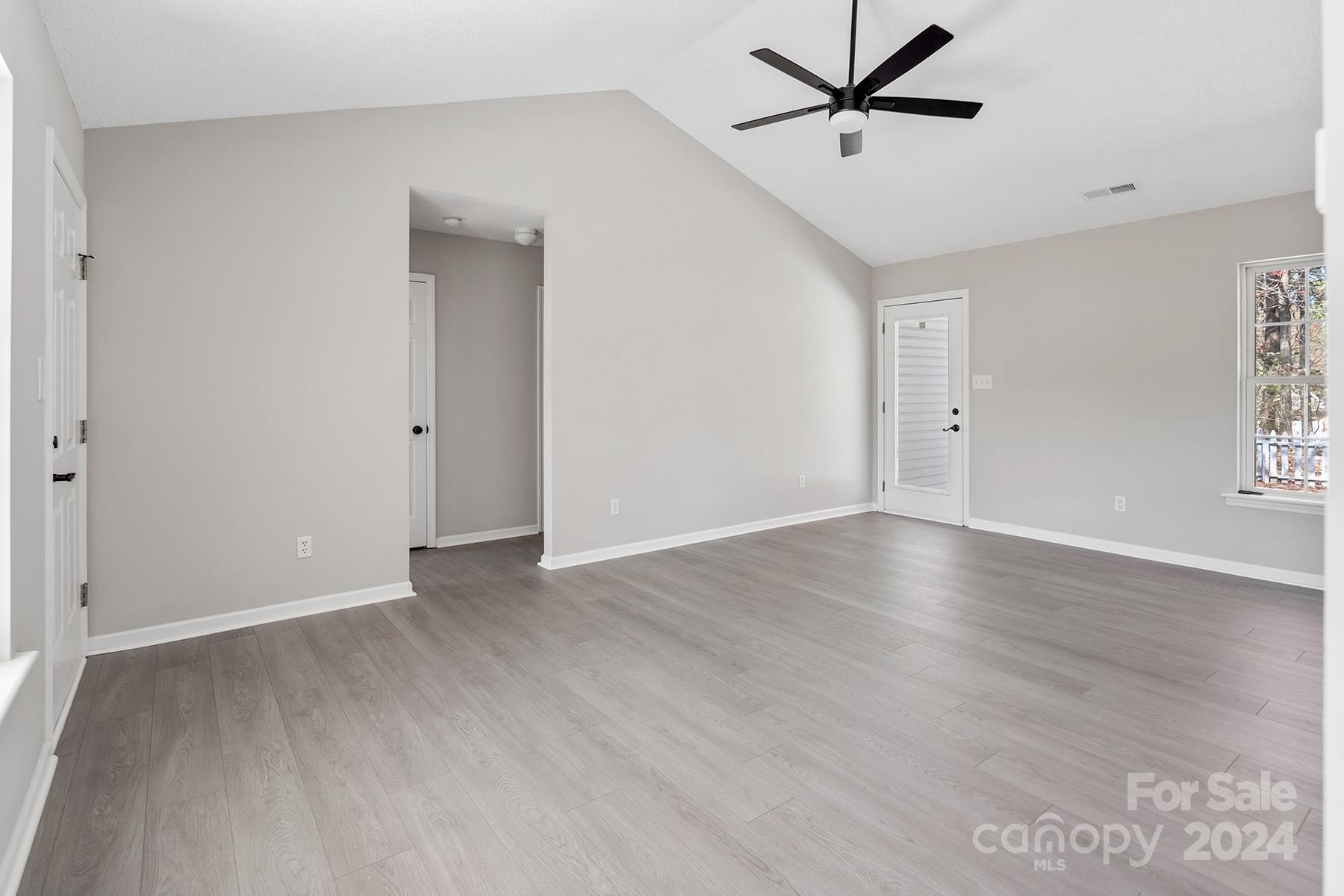 8567 Unity Church Road Denver, NC 28037 - Photo 6 of 38 an empty room with wooden floor ceiling fan and windows