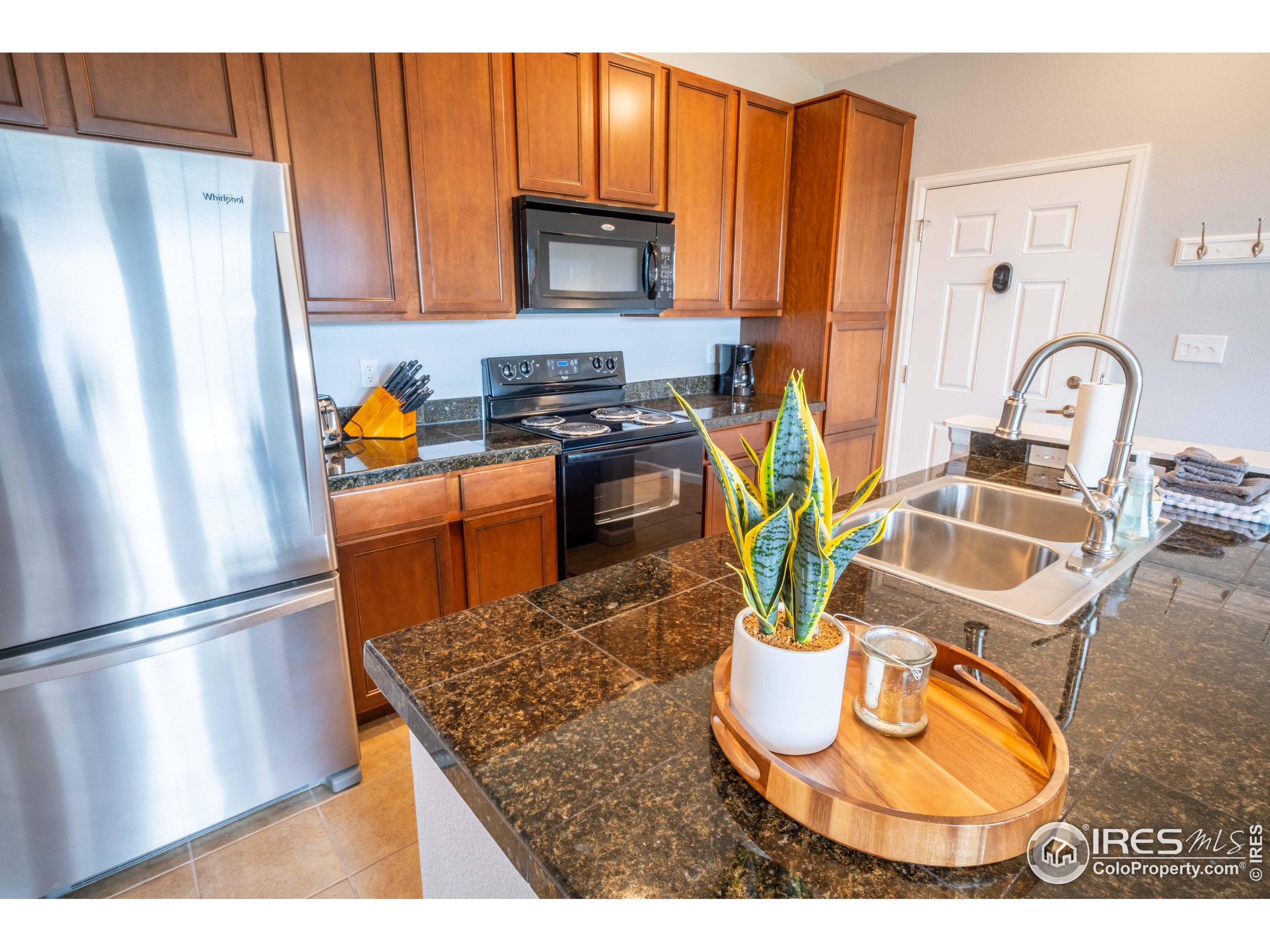 a kitchen with stainless steel appliances granite countertop a refrigerator a stove a sink a microwave and cabinets