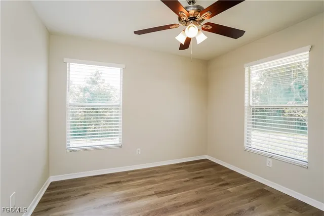 a view of an empty room with window and wooden floor