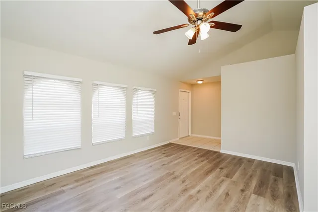 a view of an empty room with window and a kitchen