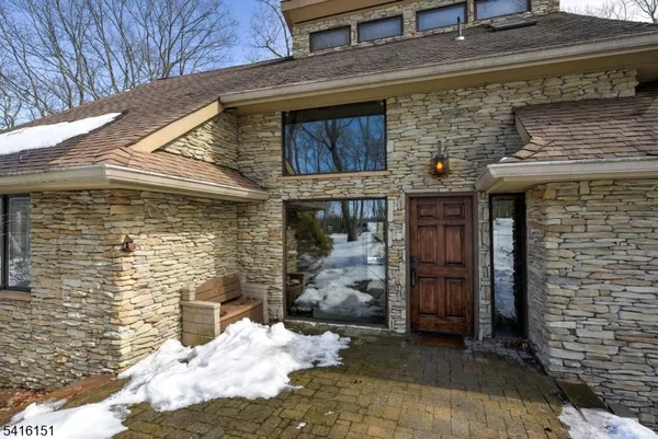 a front view of a stone house with a large tree