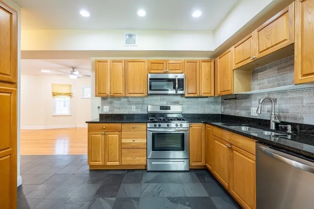 a kitchen with stainless steel appliances granite countertop a stove a sink and a microwave