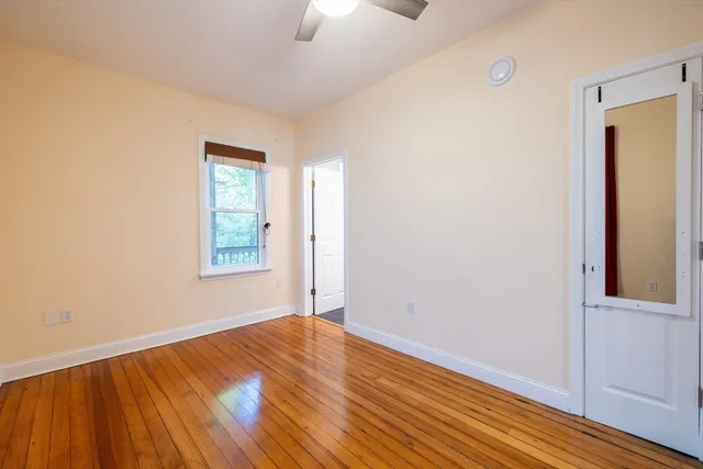 an empty room with wooden floor cabinet and windows