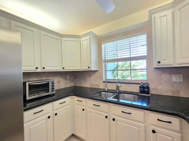 a kitchen with granite countertop white cabinets and window