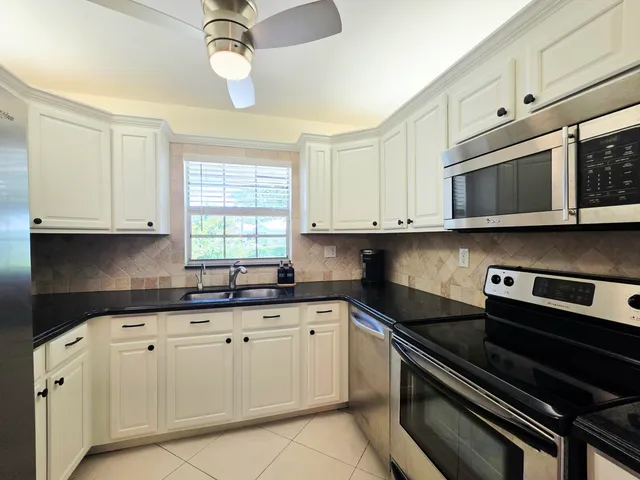 a kitchen with granite countertop white cabinets white stainless steel appliances and a sink