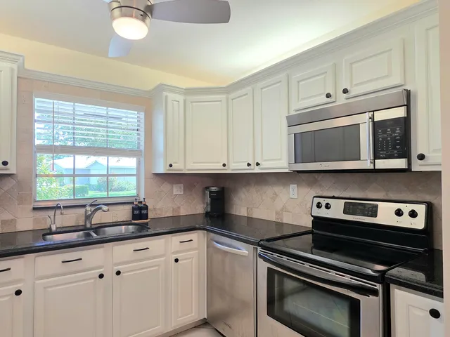 a kitchen with granite countertop a stove microwave and sink