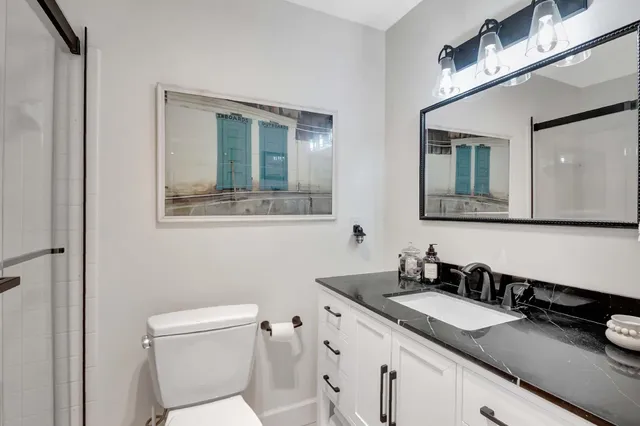 a bathroom with a granite countertop sink toilet and mirror