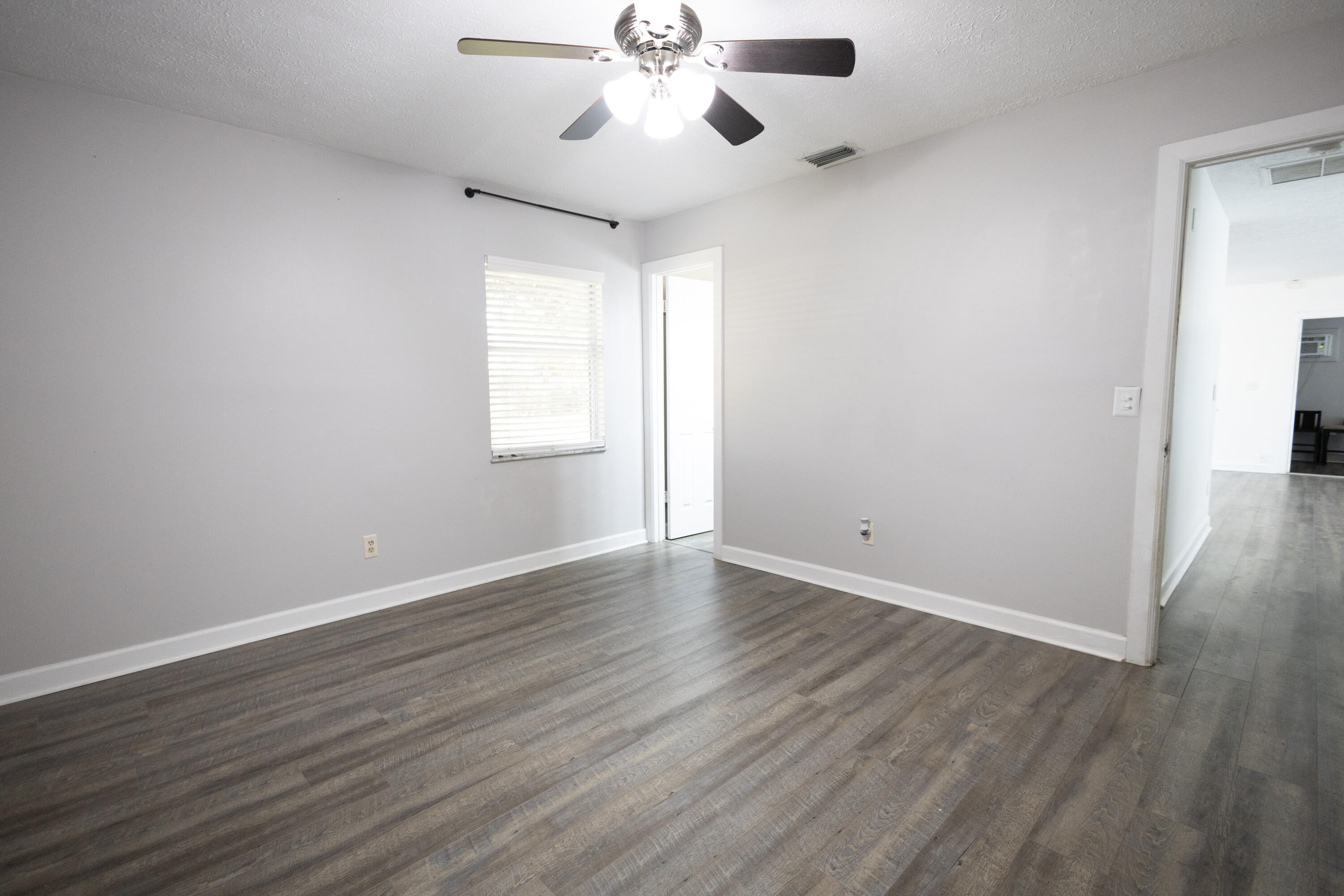 1914 Southwest Beauregard Street Port St. Lucie, FL 34953 - Photo 19 of 23 an empty room with wooden floor chandelier fan and windows