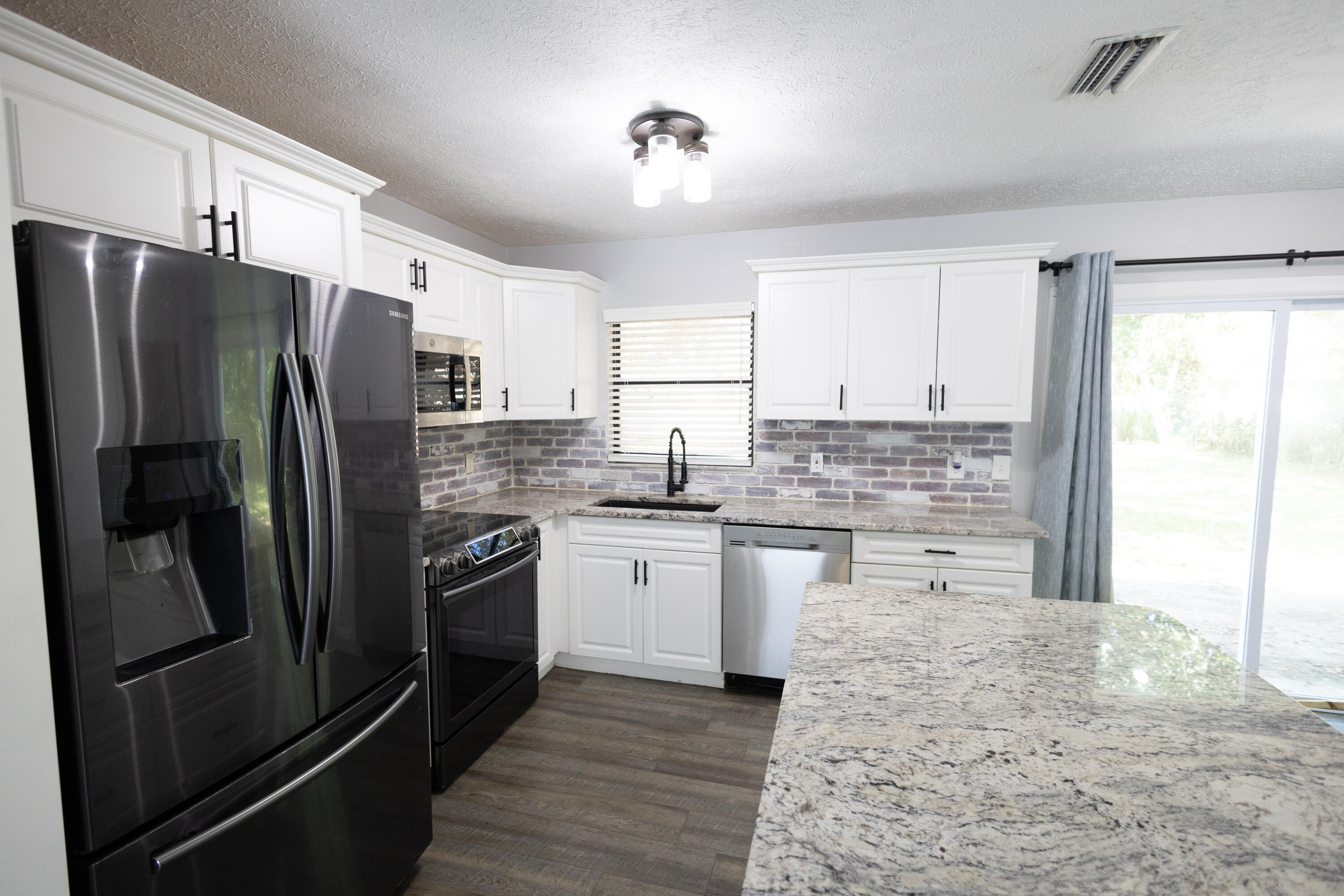 1914 Southwest Beauregard Street Port St. Lucie, FL 34953 - Photo 9 of 23 a kitchen with stainless steel appliances granite countertop a refrigerator stove top oven and sink