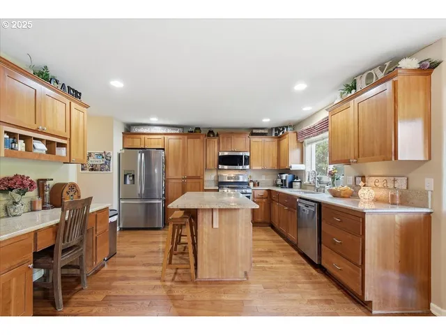 a kitchen with stainless steel appliances kitchen island granite countertop a refrigerator a stove top oven and a sink