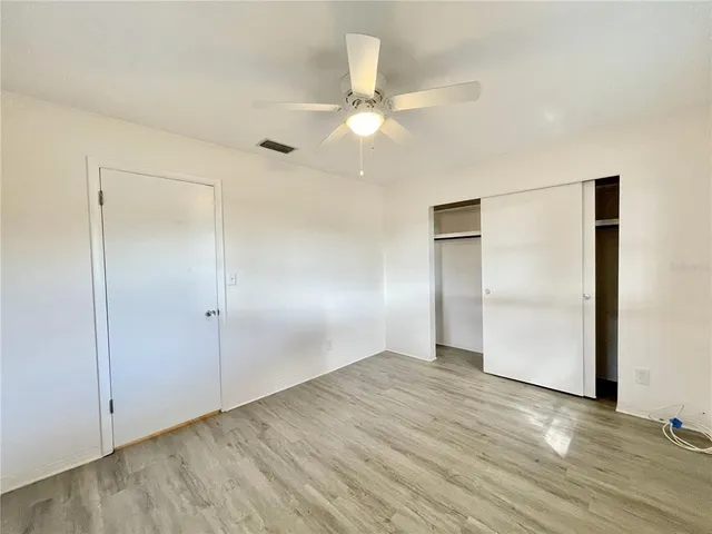 an empty room with wooden floor closet and windows