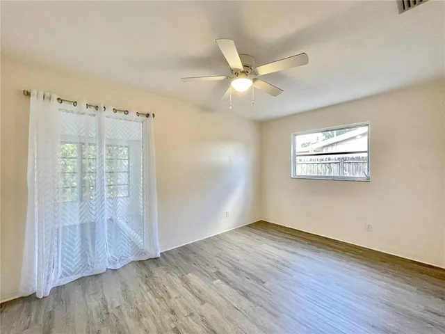 a view of an empty room with wooden floor and a window