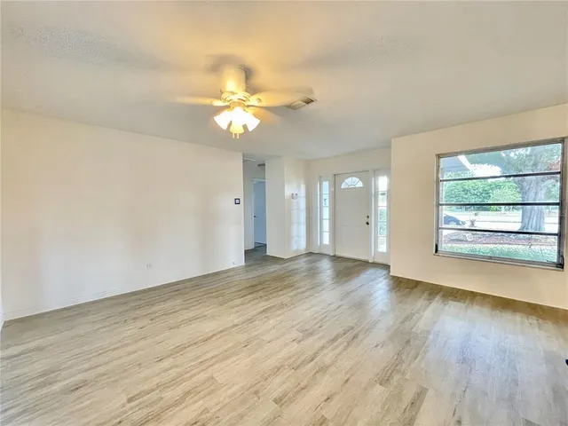 an empty room with wooden floor and window