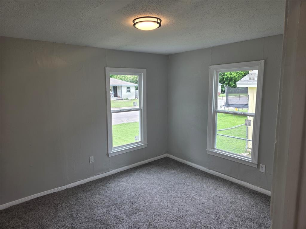 3729 Parrott Avenue Waco, TX 76707 - Photo 6 of 6 Room featuring two single-hung windows, wall-to-wall carpeting, light gray wall paint, and a ceiling-mounted flush light fixture
