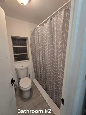 a bathroom with a toilet and a shower curtain