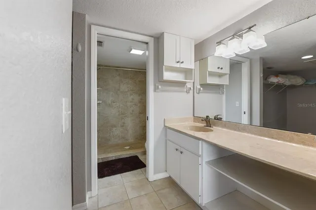 a bathroom with a granite countertop sink a mirror and a shower