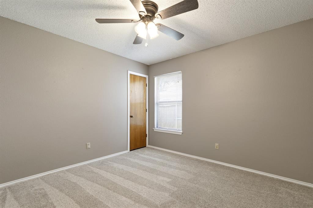 6612 Patsy Lane Watauga, TX 76148 - Photo 20 of 32 Neutral-toned room featuring a patterned carpet, a single window with blinds, and a wood-panel door