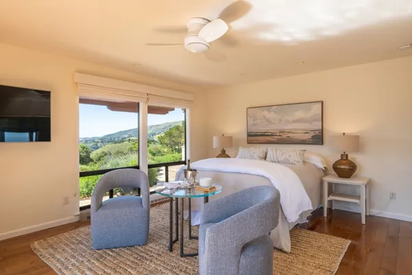 a bedroom with a bed wooden floor and a flat screen tv