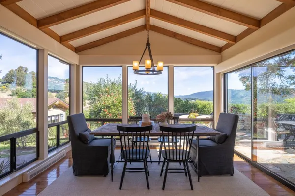 a dining room with furniture large windows and wooden floor