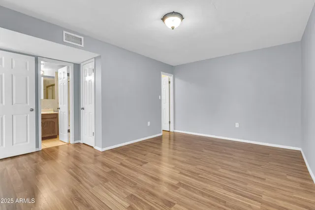 a view of an empty room with wooden floor and windows