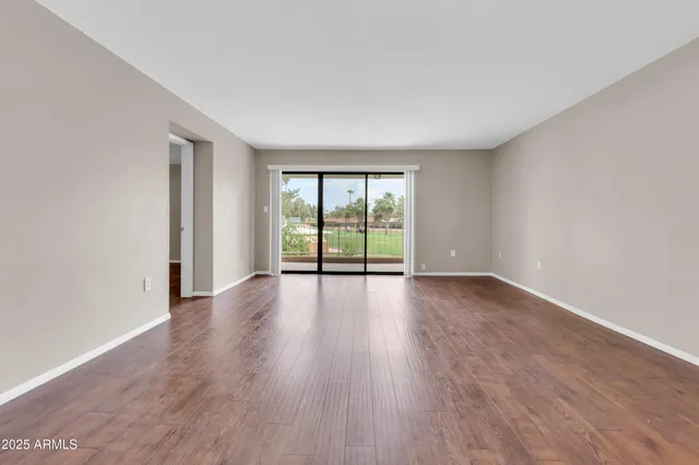 a view of an empty room with wooden floor and a window