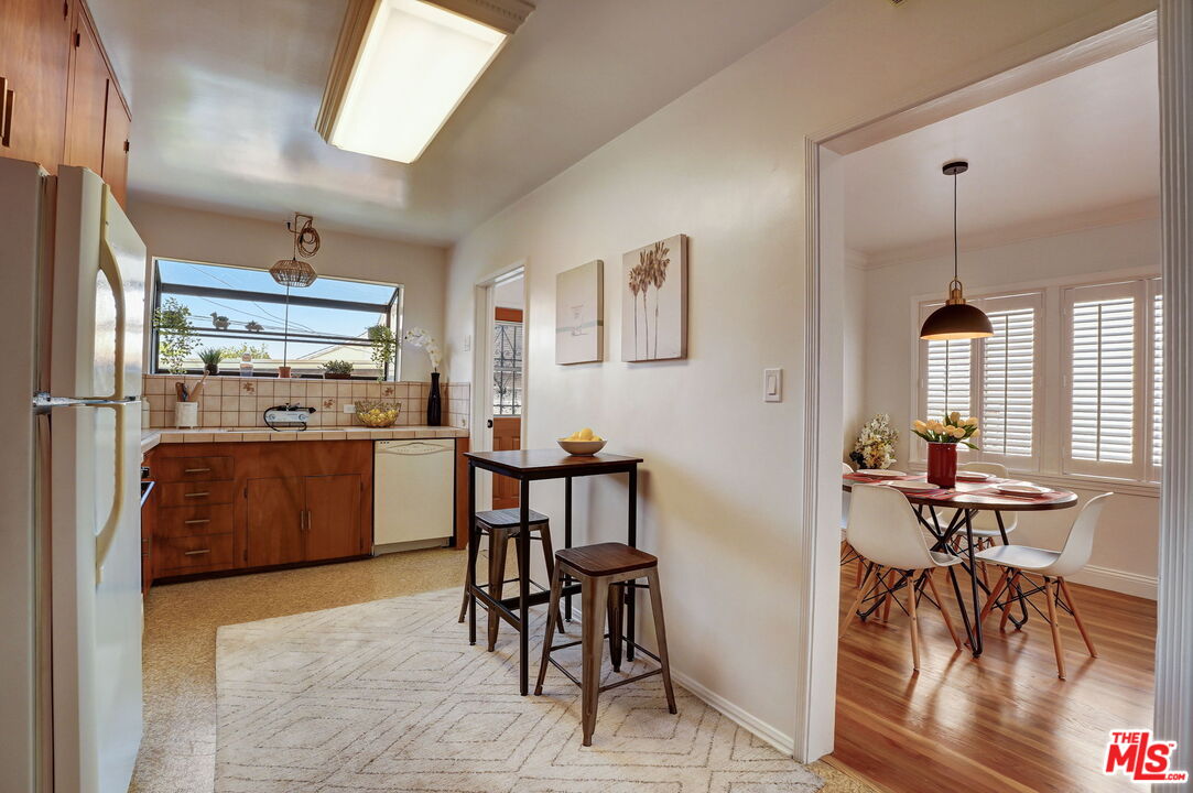 6215 West 77th Street Los Angeles, CA 90045 - Photo 9 of 23 a kitchen with stainless steel appliances kitchen island granite countertop a refrigerator a stove a dining table and chairs with wooden floor