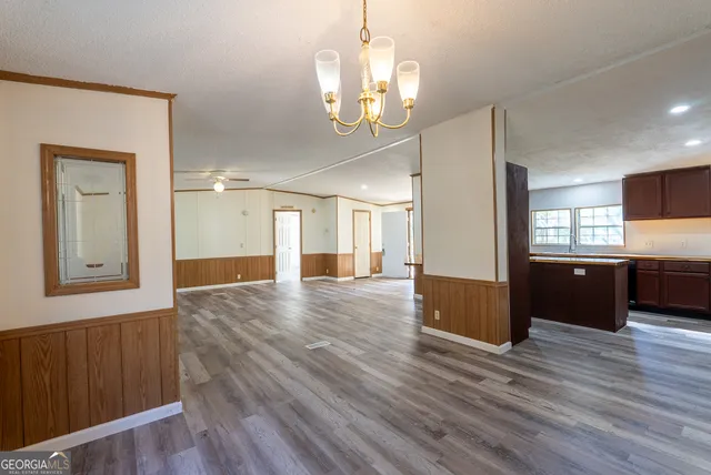 a view of a hallway with wooden floor and a kitchen