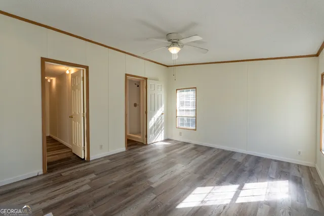 an empty room with wooden floor chandelier fan and windows