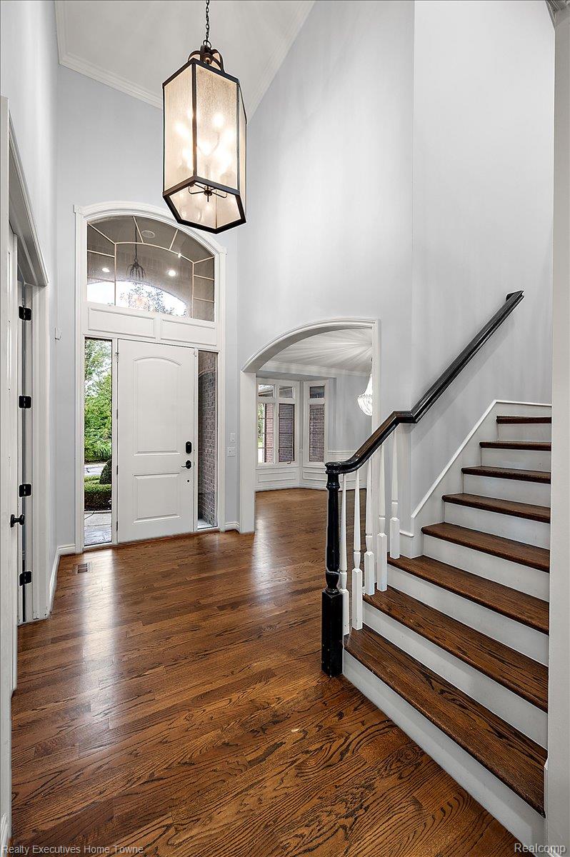 2919 North Addison Circle Rochester, MI 48306 - Photo 12 of 69 Two-story foyer with a vaulted ceiling, wood-finish flooring, a decorative chandelier, and a prominent staircase with dark wood treads and handrail