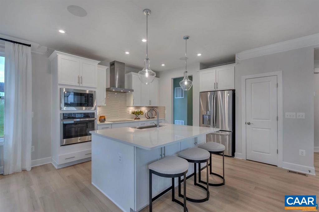 2837 Rambling Brook Lane Crozet, VA 22932 - Photo 7 of 24 a large kitchen with stainless steel appliances kitchen island granite countertop a stove a refrigerator a sink a dining table and chairs with wooden floor