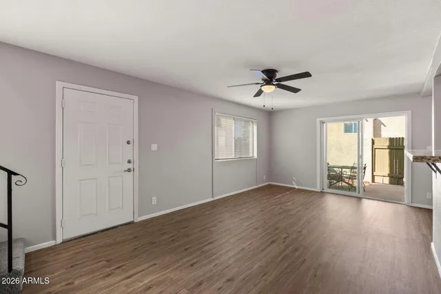an empty room with wooden floor and ceiling fan