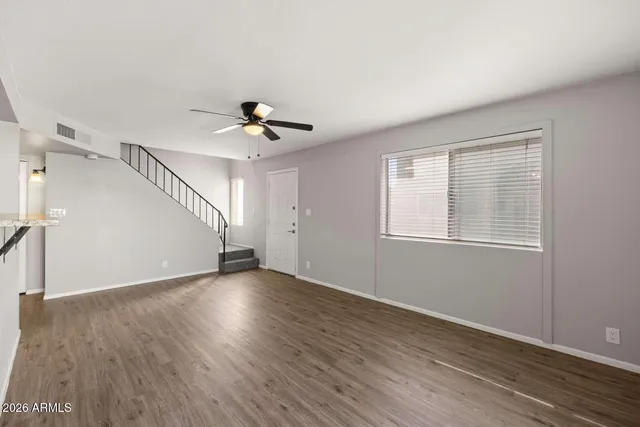a view of an empty room with wooden floor and a window